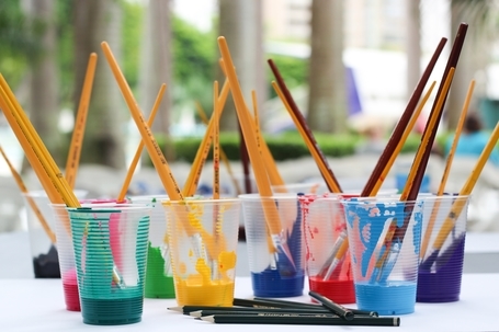 Paintbrushes in plastic cups of paint in an Art Education classroom